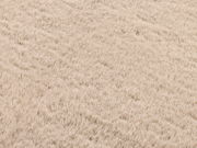 Nahaufnahme eines beigen Fellteppichs mit weicher, flauschiger Textur.