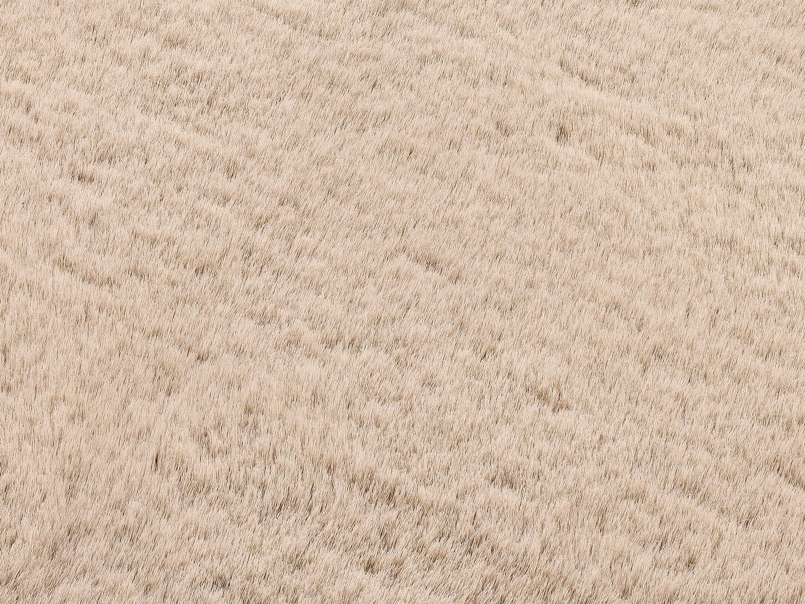 Nahaufnahme eines beigen Fellteppichs mit weicher, flauschiger Textur.