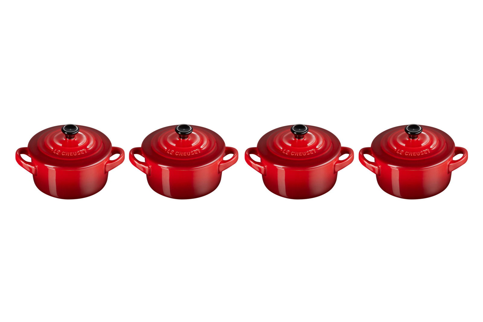 LE CREUSET Mini-Cocotte 4er-Set 10cm Kirschrot Vier kirschrote Mini-Cocottes von oben betrachtet, gleichmäßig nebeneinander angeordnet.