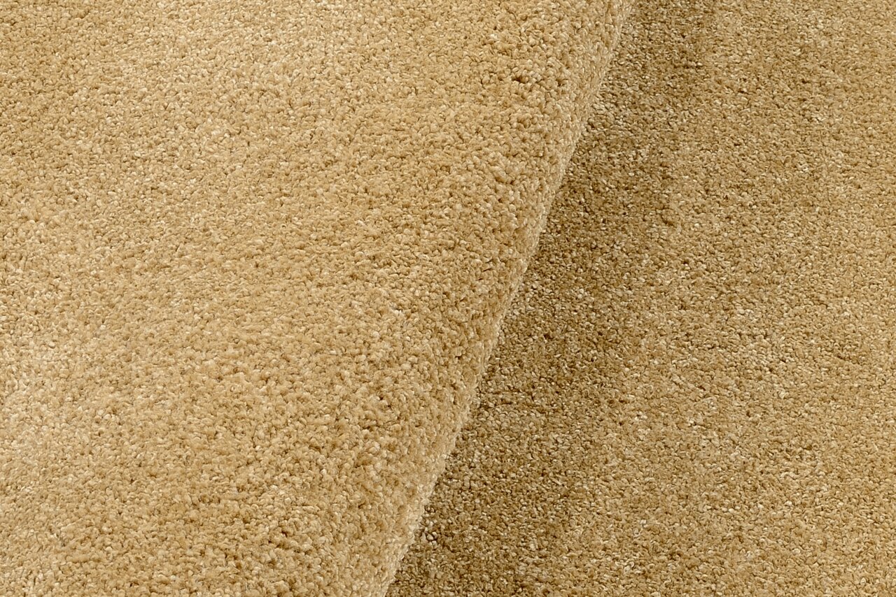 Nahaufnahme eines beigen Uni-Teppichs mit weicher Textur, von der Seite betrachtet.