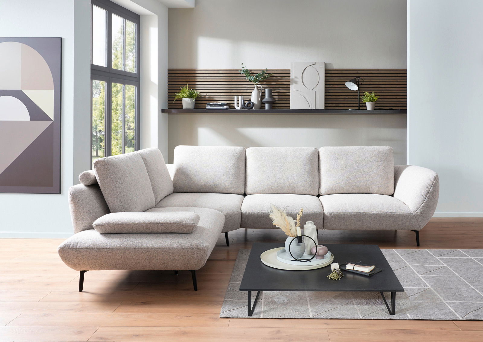 Moderne Rundecke in hellem Stoff, ausgestellt in einem stilvollen Wohnzimmer mit Holzboden und großen Fenstern, seitliche Perspektive.