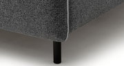 Nahaufnahme einer Ecke eines grauen Polsterbetts mit schwarzem Bein, seitliche Perspektive