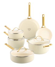 Sechsteiliges Topfset in Cremefarbe mit goldenen Griffen, bestehend aus Töpfen und Pfannen mit Glasdeckeln, frontal und leicht von oben fotografiert.