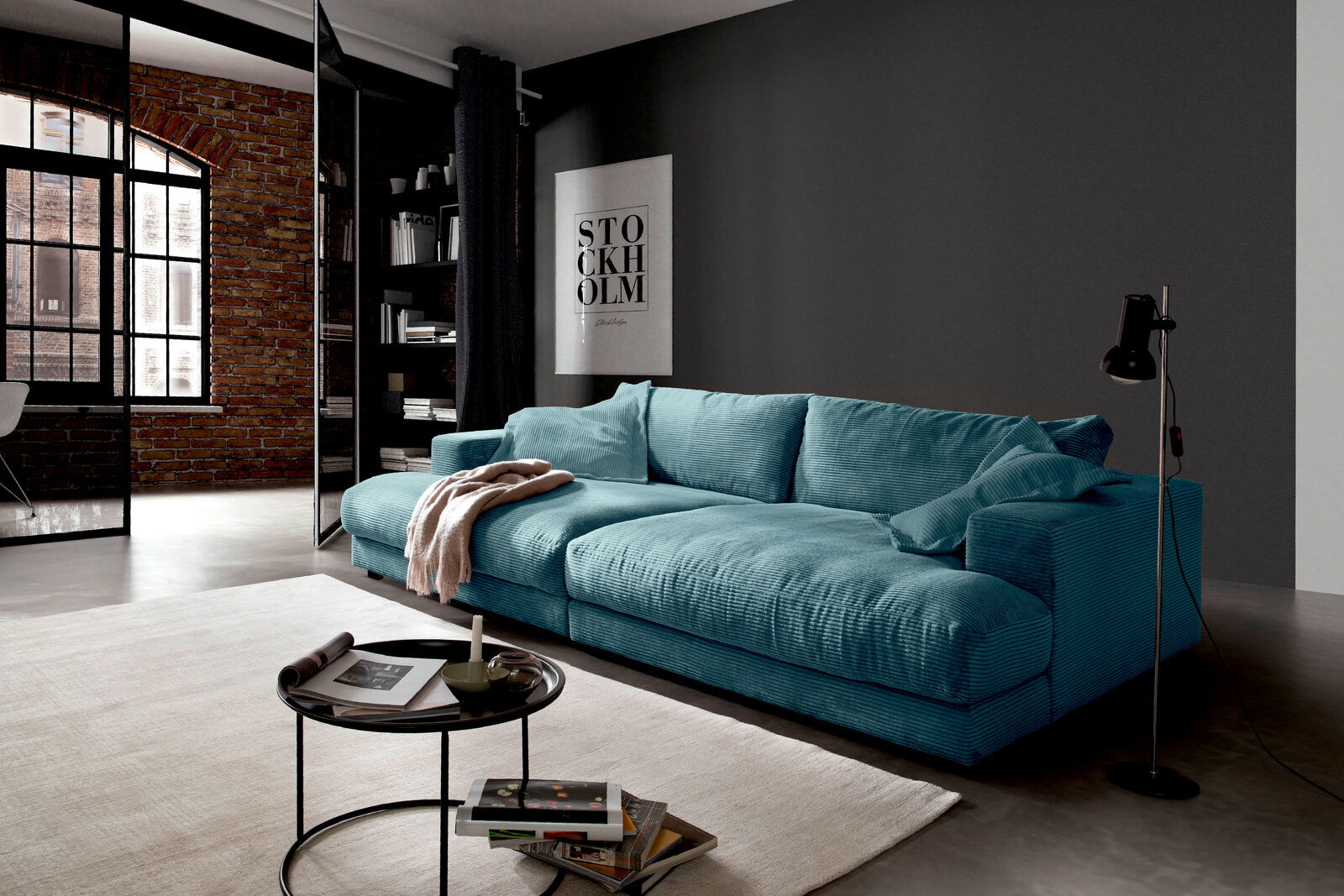 Großes, türkisfarbenes Megasofa in modernem Wohnzimmer, seitliche Perspektive