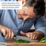 Mann schneidet Kräuter auf einem großen Schneidebrett aus Holz, Nahaufnahme