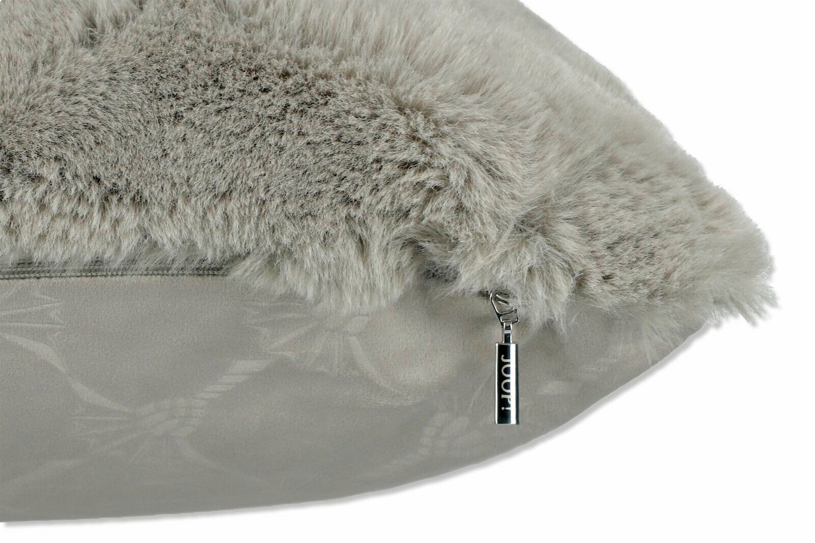 Nahaufnahme eines flauschigen, grauen Kissens mit Reißverschluss und dekorativem Muster, seitliche Perspektive.