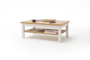 Moderner Couchtisch aus Holz mit weißem Gestell, von schräg oben fotografiert. Auf der Tischplatte befinden sich eine Tasse, eine Schale und eine Fernbedienung. Auf der unteren Ablage liegen Bücher.