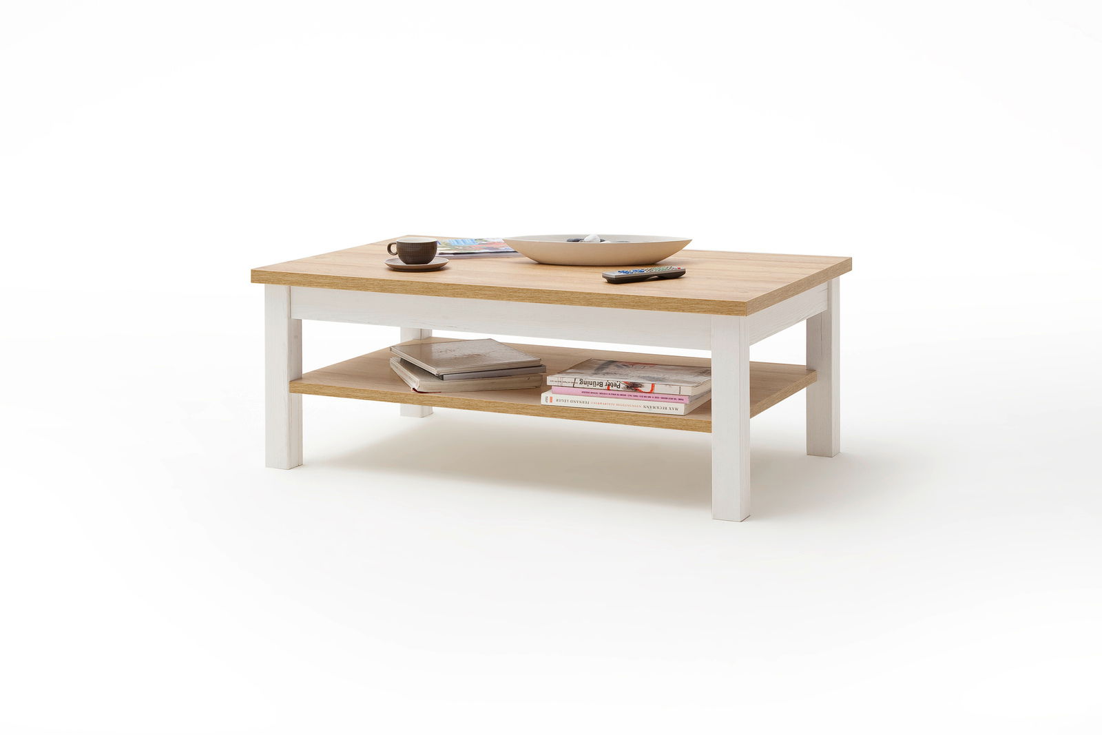 Moderner Couchtisch aus Holz mit weißem Gestell, von schräg oben fotografiert. Auf der Tischplatte befinden sich eine Tasse, eine Schale und eine Fernbedienung. Auf der unteren Ablage liegen Bücher.