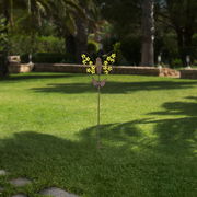 Solarleuchte in Schmetterlingsform auf einer Wiese, frontal fotografiert.