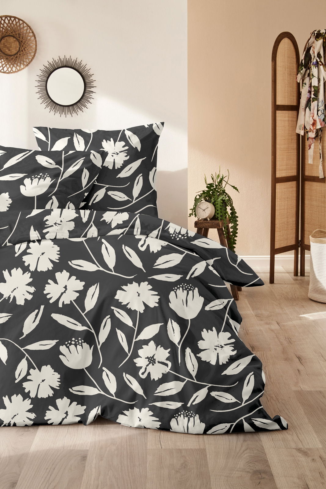 Bettwäsche-Set mit floralem Muster in Schwarz-Weiß, fotografiert aus einer seitlichen Perspektive im Schlafzimmer.