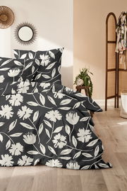 Bettwäsche-Set mit floralem Muster in Schwarz-Weiß, fotografiert aus einer seitlichen Perspektive im Schlafzimmer.