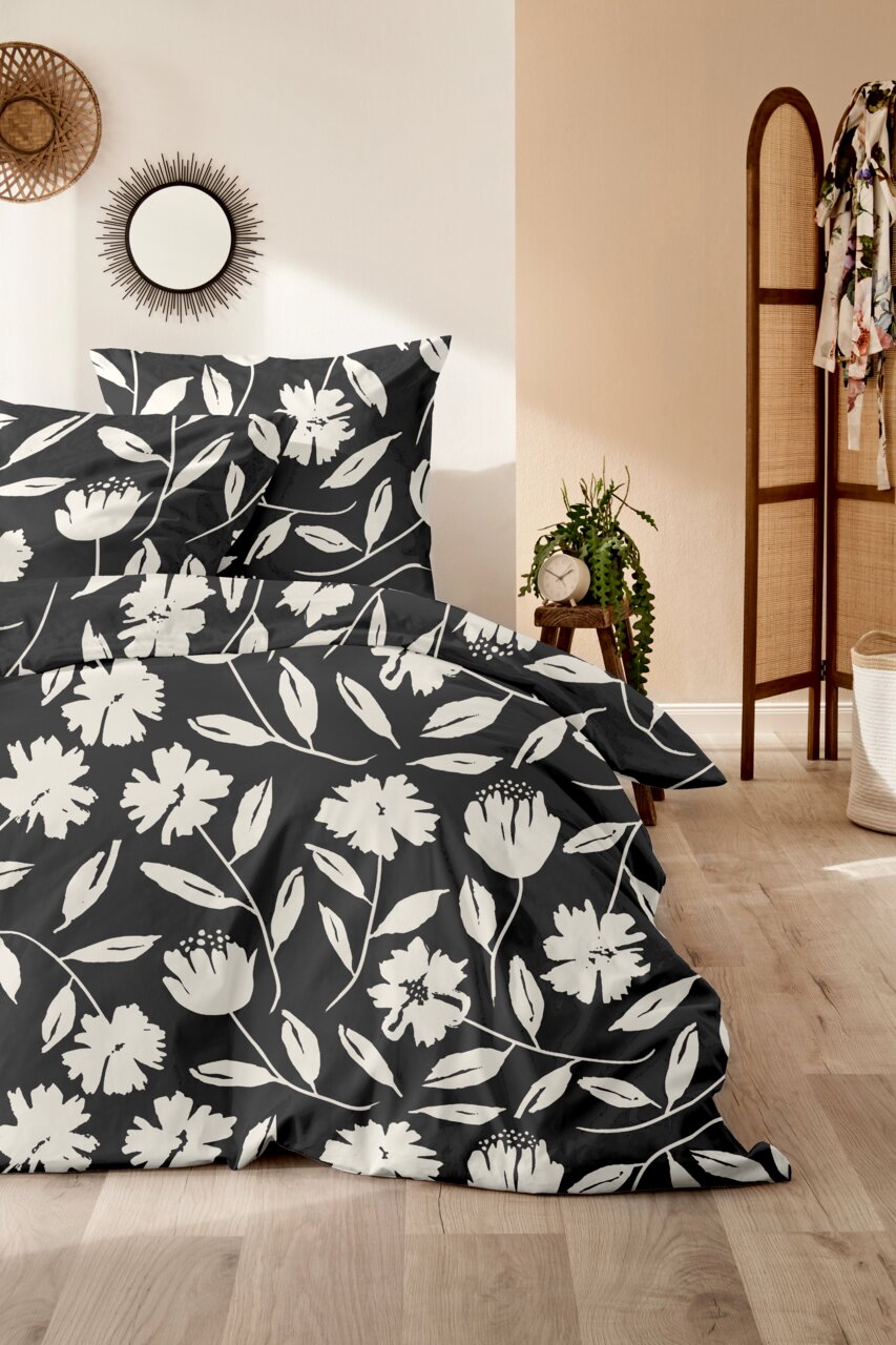 Bettwäsche-Set mit floralem Muster in Schwarz-Weiß, fotografiert aus einer seitlichen Perspektive im Schlafzimmer.