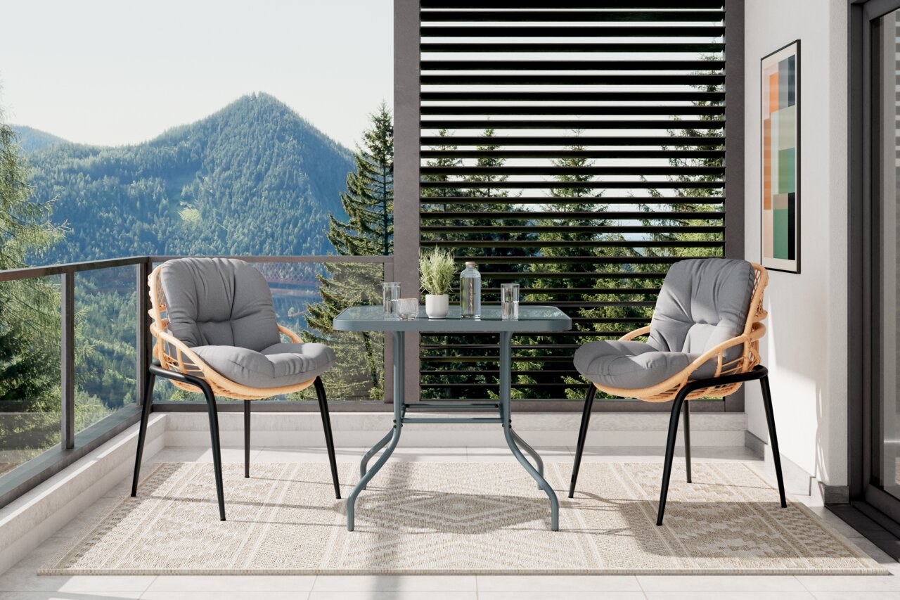 Zwei Gartensessel mit grauen Kissen auf einem Balkon mit Bergblick, aus seitlicher Perspektive fotografiert.