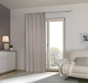 Fertigvorhang in einem modernen Wohnzimmer, aufgehängt an einer Gardinenstange vor einer Glastür, mit Blick auf einen hellen, gemütlichen Raum.