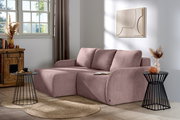 L-förmiges Sofa in einem modernen Wohnzimmer, aus einer seitlichen Perspektive fotografiert. Das Sofa hat eine rosa Farbe und ist mit Kissen ausgestattet. Es steht auf einem Holzboden neben einem runden Beistelltisch und einer Kommode.