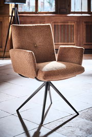 Moderner Armlehnstuhl mit braunem Stoffbezug und schwarzem Metallgestell, seitliche Perspektive