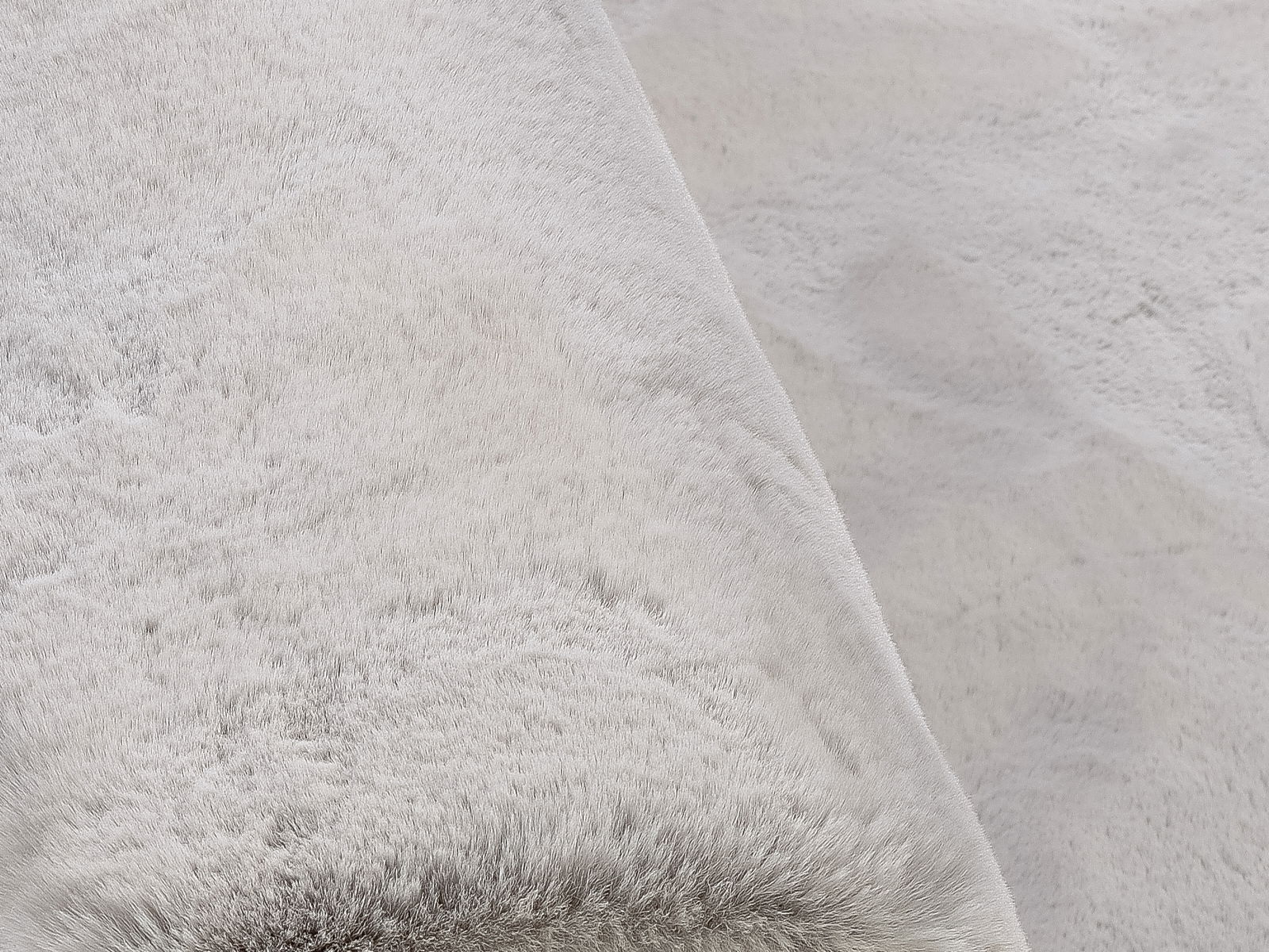 Nahaufnahme eines weichen, hellgrauen Fellteppichs aus der Vogelperspektive