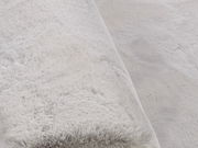 Nahaufnahme eines weichen, hellgrauen Fellteppichs aus der Vogelperspektive