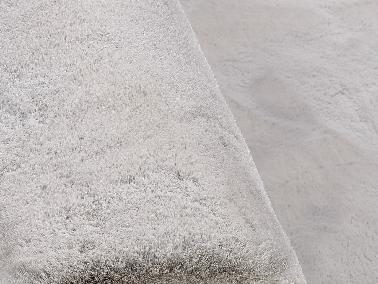 Nahaufnahme eines weichen, hellgrauen Fellteppichs aus der Vogelperspektive