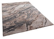 Moderner Webteppich mit abstraktem Muster in Erdtönen, perspektivisch von der Seite fotografiert.