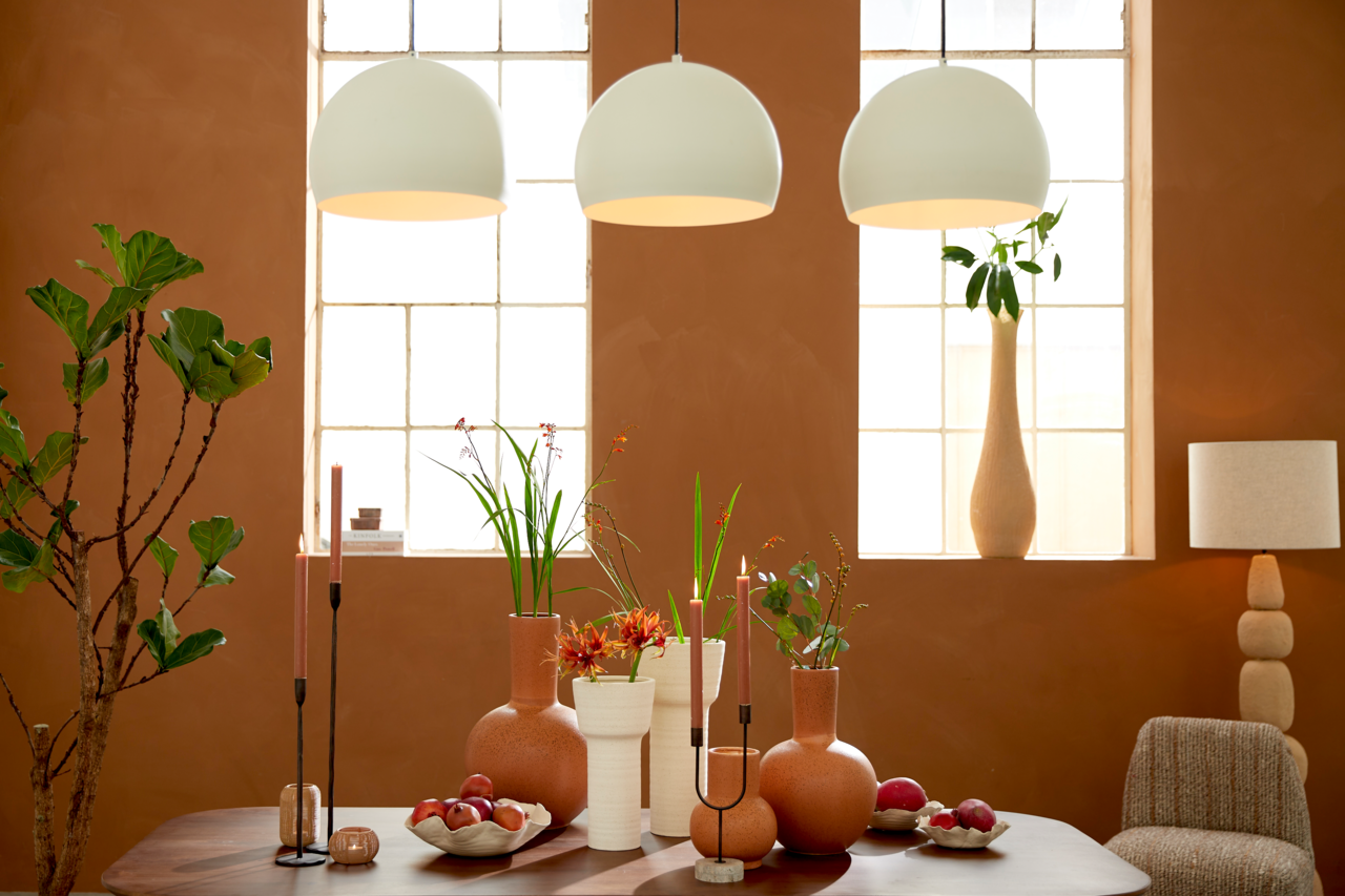 Light&Living Schale BANDA Ø31cm Ein stilvoll gedeckter Tisch mit einer Schale voller roter Früchte, umgeben von modernen Vasen und Kerzenhaltern, aus der Perspektive von vorne betrachtet.