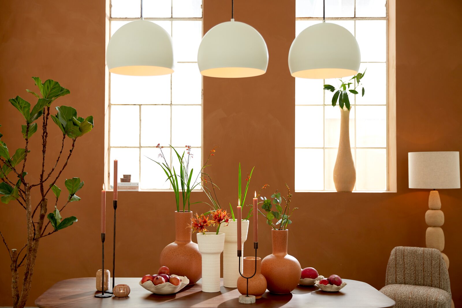 Light&Living Schale BANDA Ø31cm Ein stilvoll gedeckter Tisch mit einer Schale voller roter Früchte, umgeben von modernen Vasen und Kerzenhaltern, aus der Perspektive von vorne betrachtet.