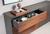 Modernes Sideboard mit geöffneten Schubladen, die Keramikgeschirr und eine Holzschale mit Dekoration zeigen. Perspektive von schräg oben.