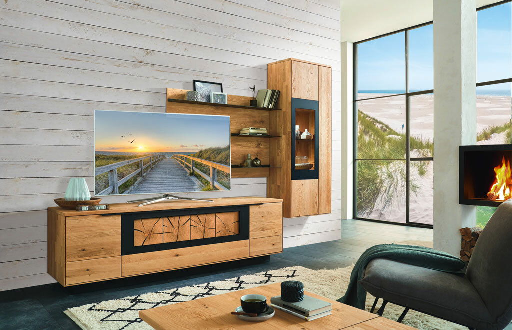 Moderne Wandkombination aus Holz in einem gemütlichen Wohnzimmer mit Kamin und großem Fenster mit Strandblick, seitliche Perspektive.