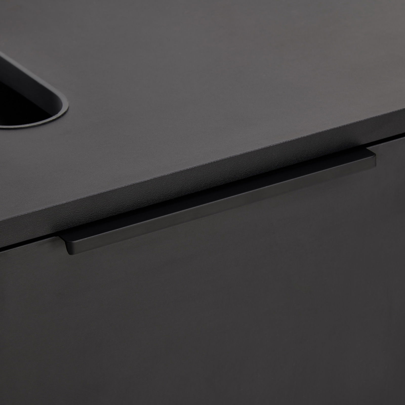 Nahaufnahme eines modernen, schwarzen Waschbeckenunterschranks mit glatter Oberfläche und integriertem Griff.