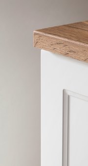 Nahaufnahme eines Waschbeckenunterschranks mit weißer Front und Holzoberfläche, seitliche Perspektive