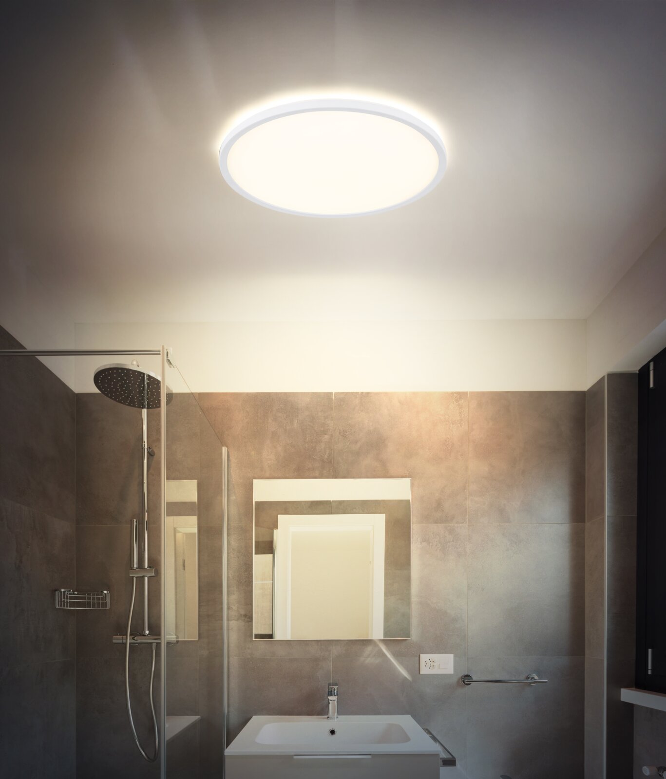Runde, flache LED-Deckenleuchte mit warmweißem Licht in modernem Badezimmer, Aufnahme aus Untersicht nach oben zur Decke