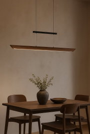 Moderne LED-Pendelleuchte über einem Esstisch aus Holz, seitliche Perspektive