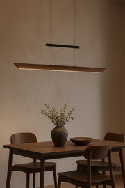 Moderne LED-Pendelleuchte über einem Esstisch aus Holz, seitliche Perspektive