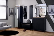 Moderne Garderobeneinrichtung mit schwarzem Garderobenpaneel, Garderobenschrank, Spiegel und Garderobenbank in einem stilvollen Raum mit Holzboden, aus der Perspektive von vorne betrachtet.