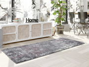 Moderner Designer Teppich in Grau- und Rottönen, in einem stilvoll eingerichteten Wohnzimmer mit Blick auf ein Sideboard und Pflanzen, aus einer seitlichen Perspektive fotografiert.