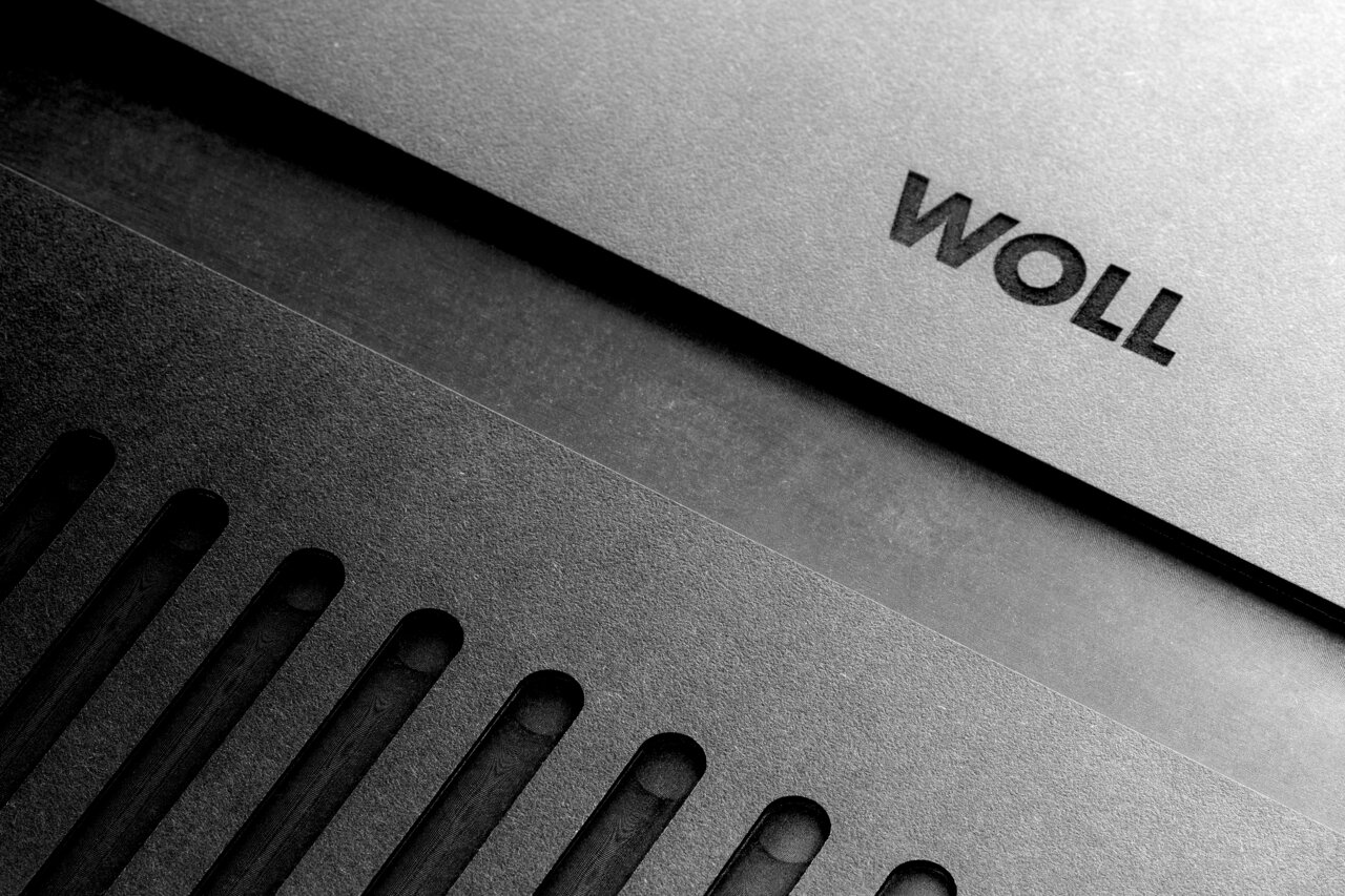 Close-up van een snijplank met groeven en het opschrift 'WOLL', gezien vanuit vogelperspectief.