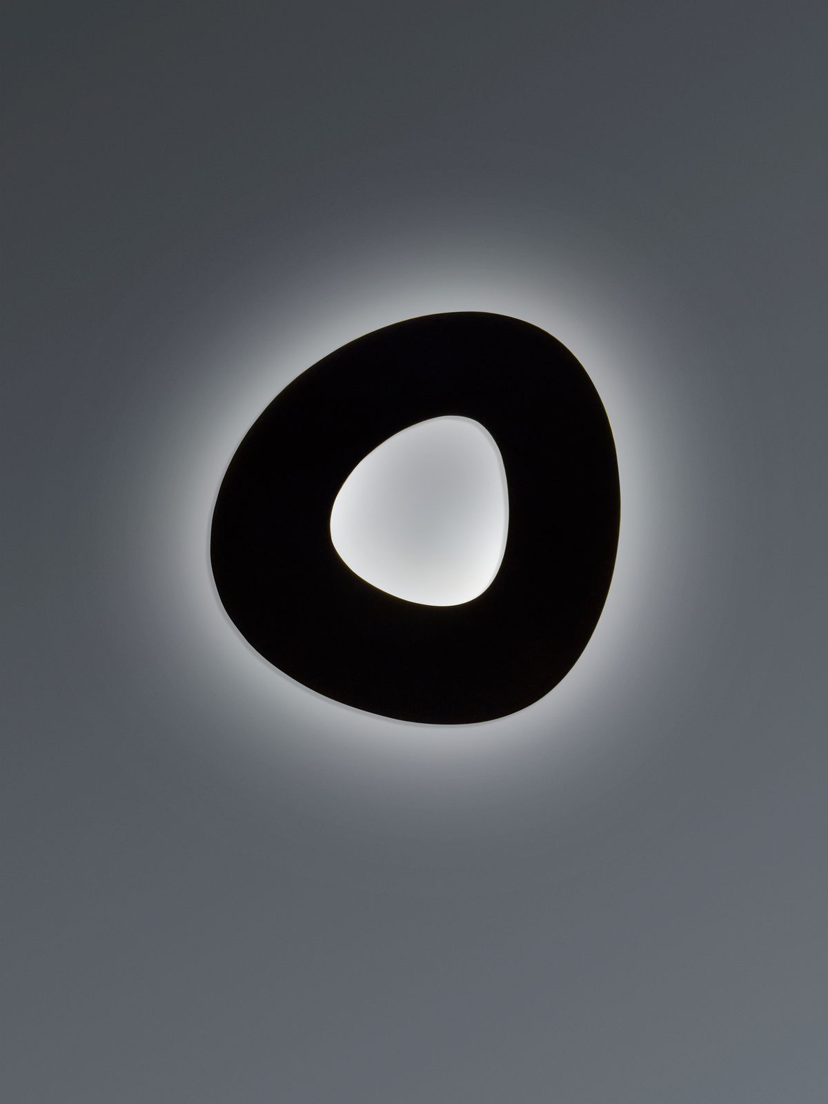 Moderne LED-Deckenleuchte in organischer Form, von unten betrachtet, mit sanftem Lichtschein an der Decke.