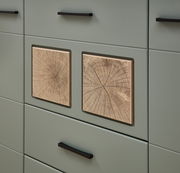 Detailansicht einer Wohnwand mit grünlichen Schubladen und dekorativen Holzeinsätzen in Baumringoptik.