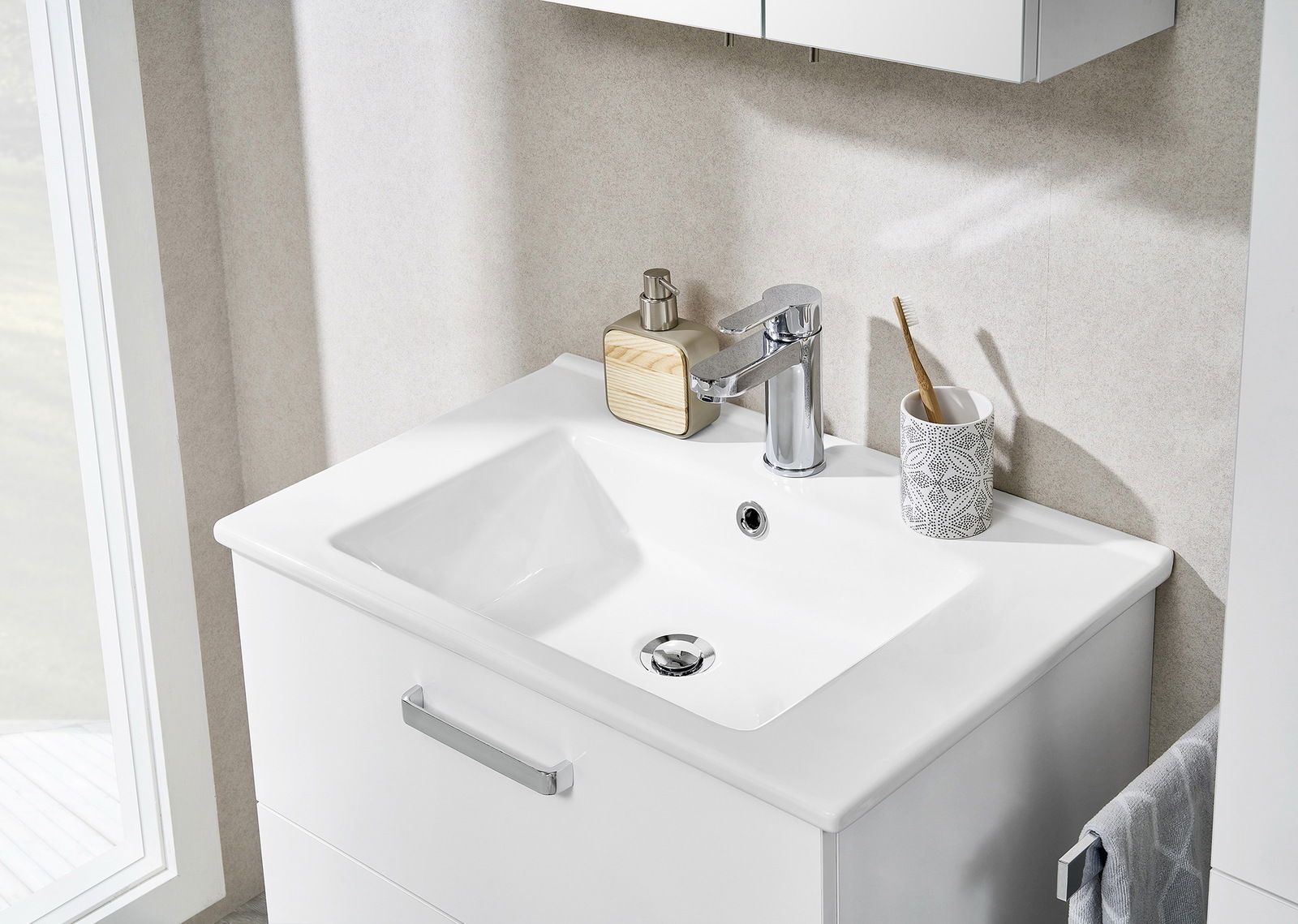 Moderner Waschtisch mit Armatur, Seifenspender und Zahnputzbecher, aus der Vogelperspektive fotografiert.