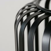 Nahaufnahme eines schwarzen, runden Windlichts mit geschwungenen Metallstreben, seitliche Perspektive