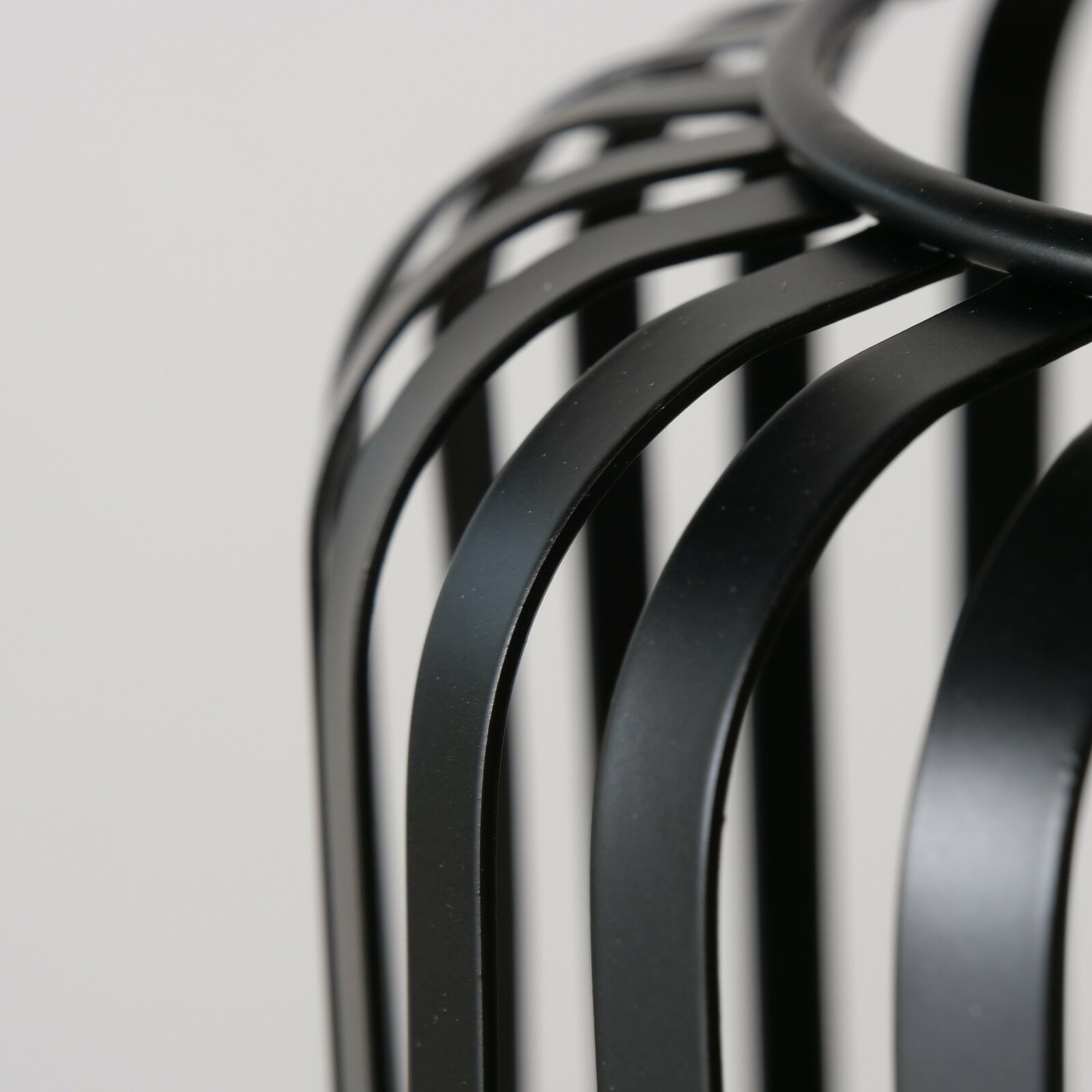 Nahaufnahme eines schwarzen, runden Windlichts mit geschwungenen Metallstreben, seitliche Perspektive