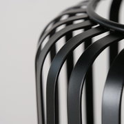 Nahaufnahme eines schwarzen, runden Windlichts mit geschwungenen Metallstreben, seitliche Perspektive