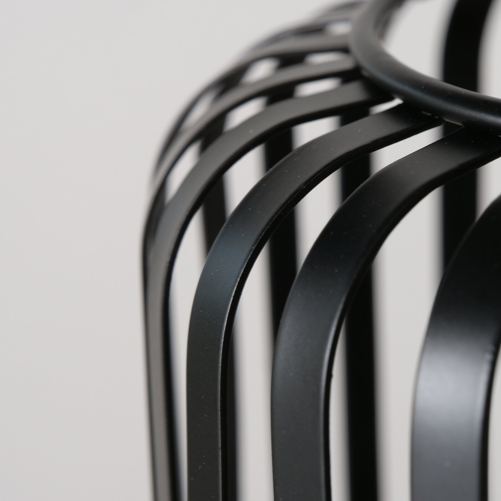 Nahaufnahme eines schwarzen, runden Windlichts mit geschwungenen Metallstreben, seitliche Perspektive