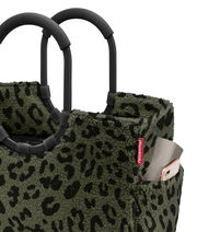 Nahaufnahme einer Tasche mit Leopardenmuster und schwarzen Griffen, seitliche Perspektive.