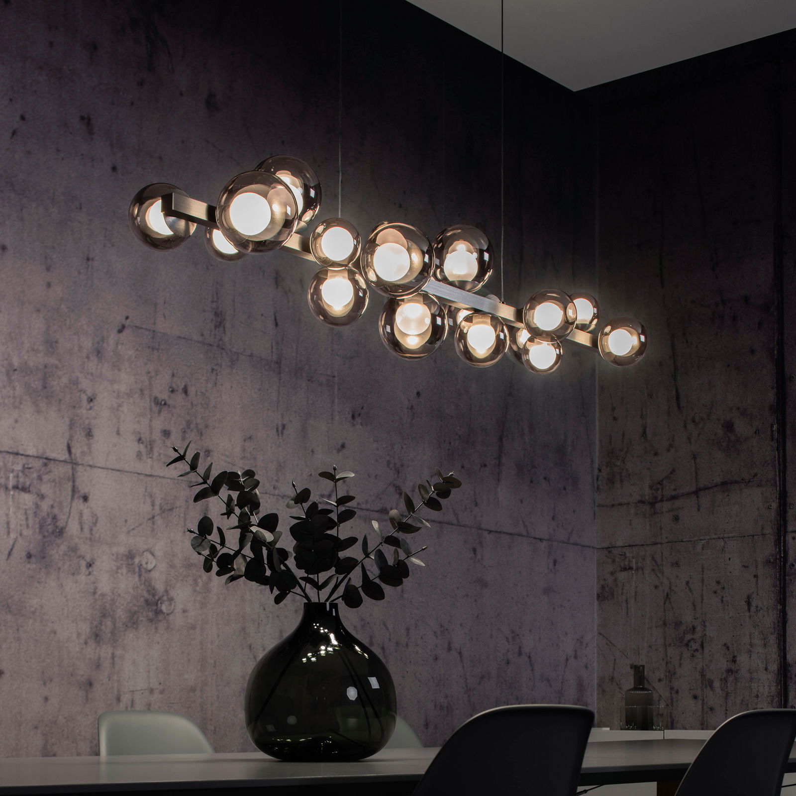 Moderne LED-Pendelleuchte mit mehreren kugelförmigen Leuchten, hängend über einem Esstisch in einem stilvoll eingerichteten Raum, seitliche Perspektive.