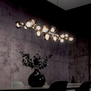 Moderne LED-Pendelleuchte mit mehreren kugelförmigen Leuchten, hängend über einem Esstisch in einem stilvoll eingerichteten Raum, seitliche Perspektive.