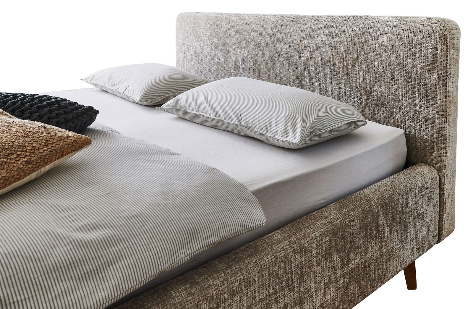 Seitliche Perspektive auf ein Polsterbett mit beigem Stoffbezug, zwei Kissen und einer gestreiften Bettdecke.
