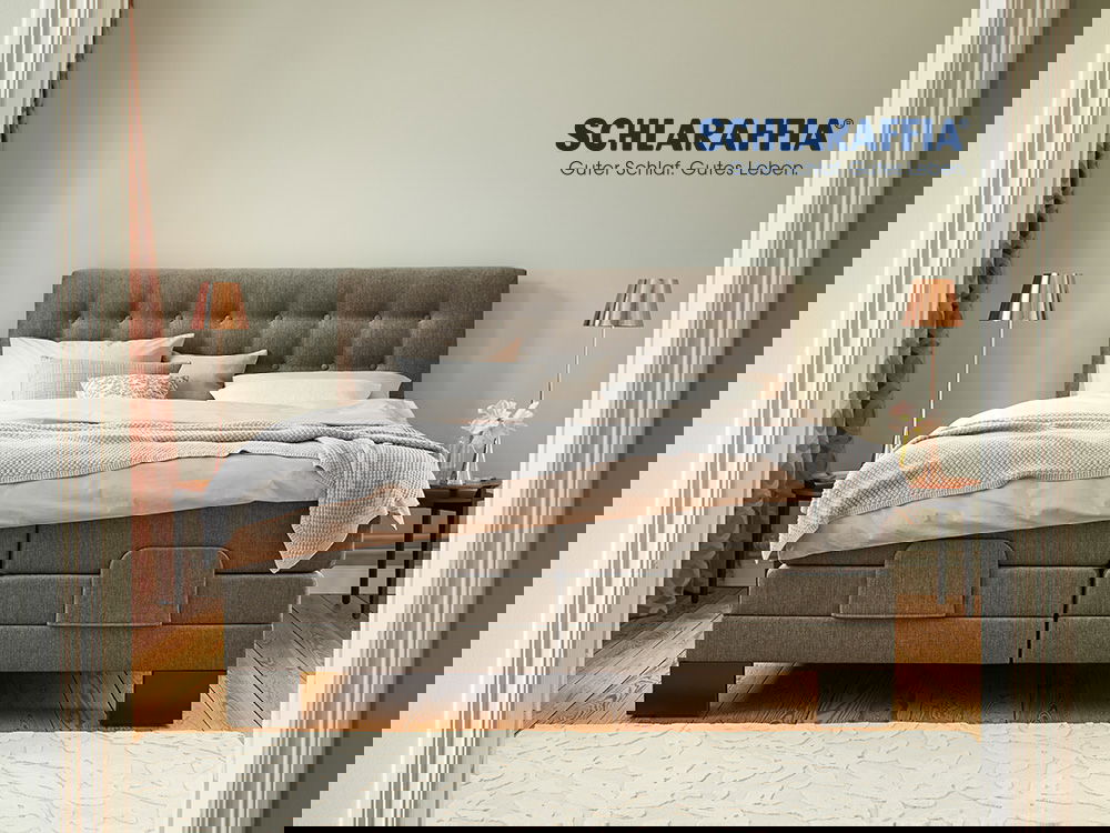 Gemütliches Schlafzimmer mit einem eleganten Schlaraffia-Boxspringbett in warmen Farbtönen.