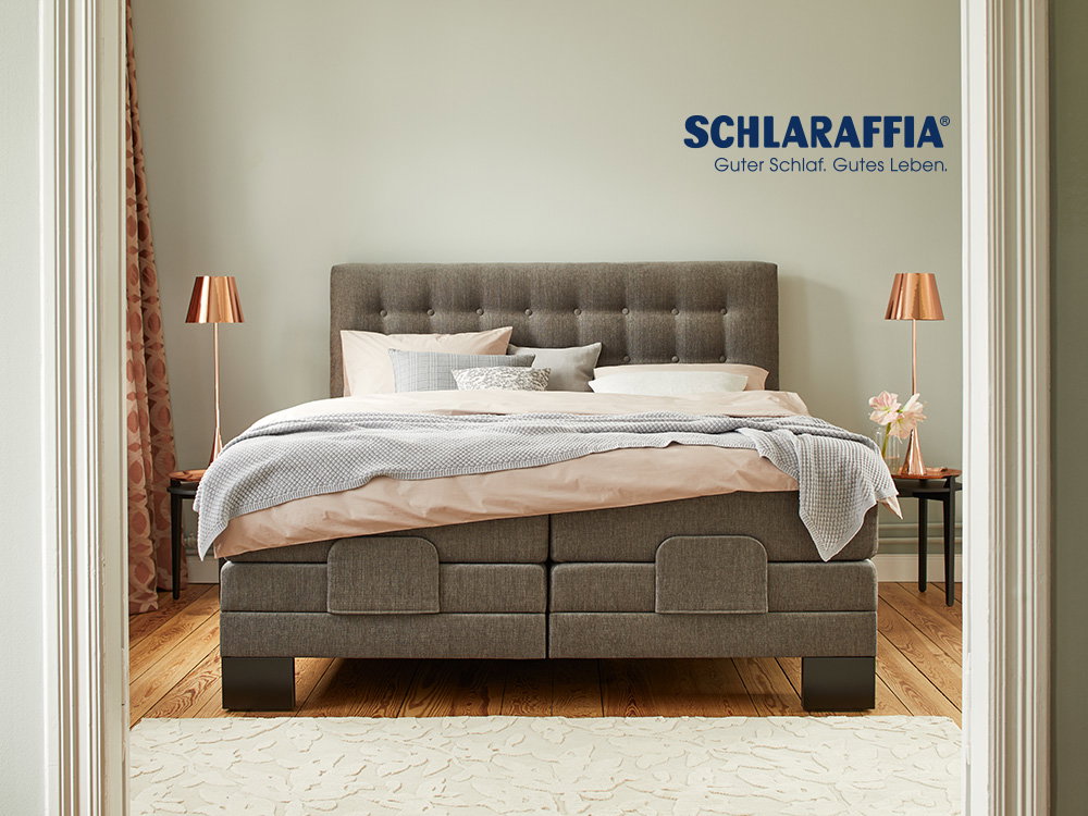 Gemütliches Schlafzimmer mit einem eleganten Schlaraffia-Boxspringbett in warmen Farbtönen.