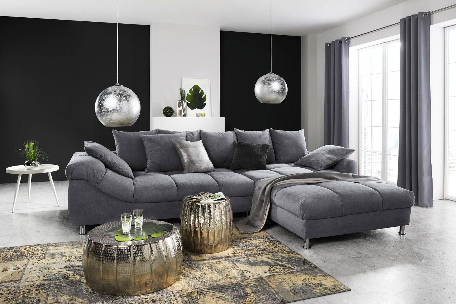 Graue Rundecke (L) in einem modernen Wohnzimmer, seitliche Perspektive, mit dekorativen Kissen und Decke, umgeben von stilvollen Möbeln und großen Fenstern.